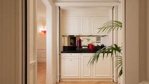 A narrow hallway leading to a kitchen with white cabinetry, a black countertop, and a red appliance. - Palazzo Ripetta (Rome)
