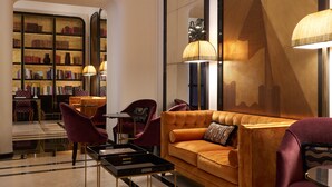 A modern lounge area with a leather sofa, matching armchairs, a coffee table, and a bookshelf filled with books. - Palazzo Ripetta (Rome)