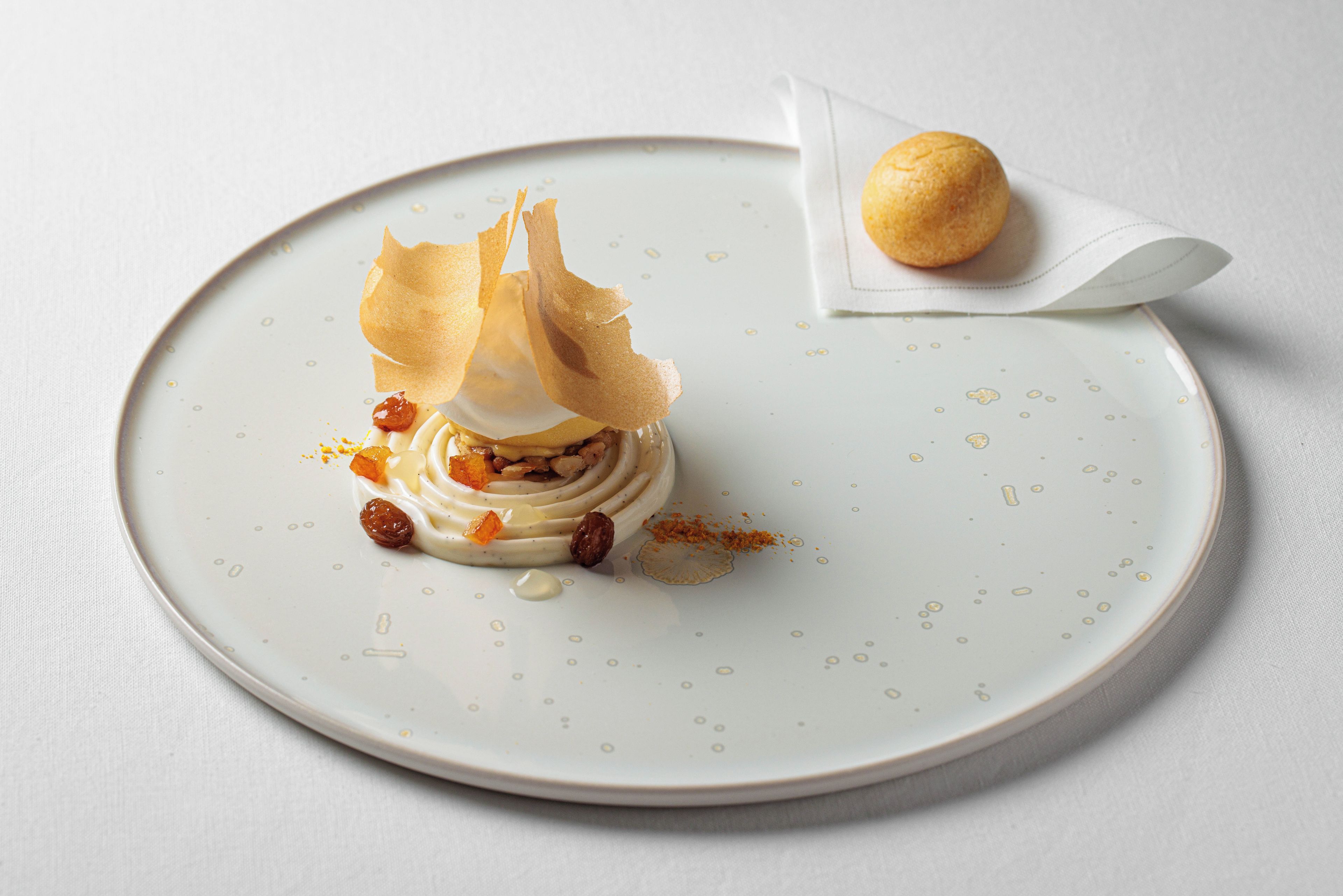 A dessert on a plate with a small pastry on a napkin beside it.