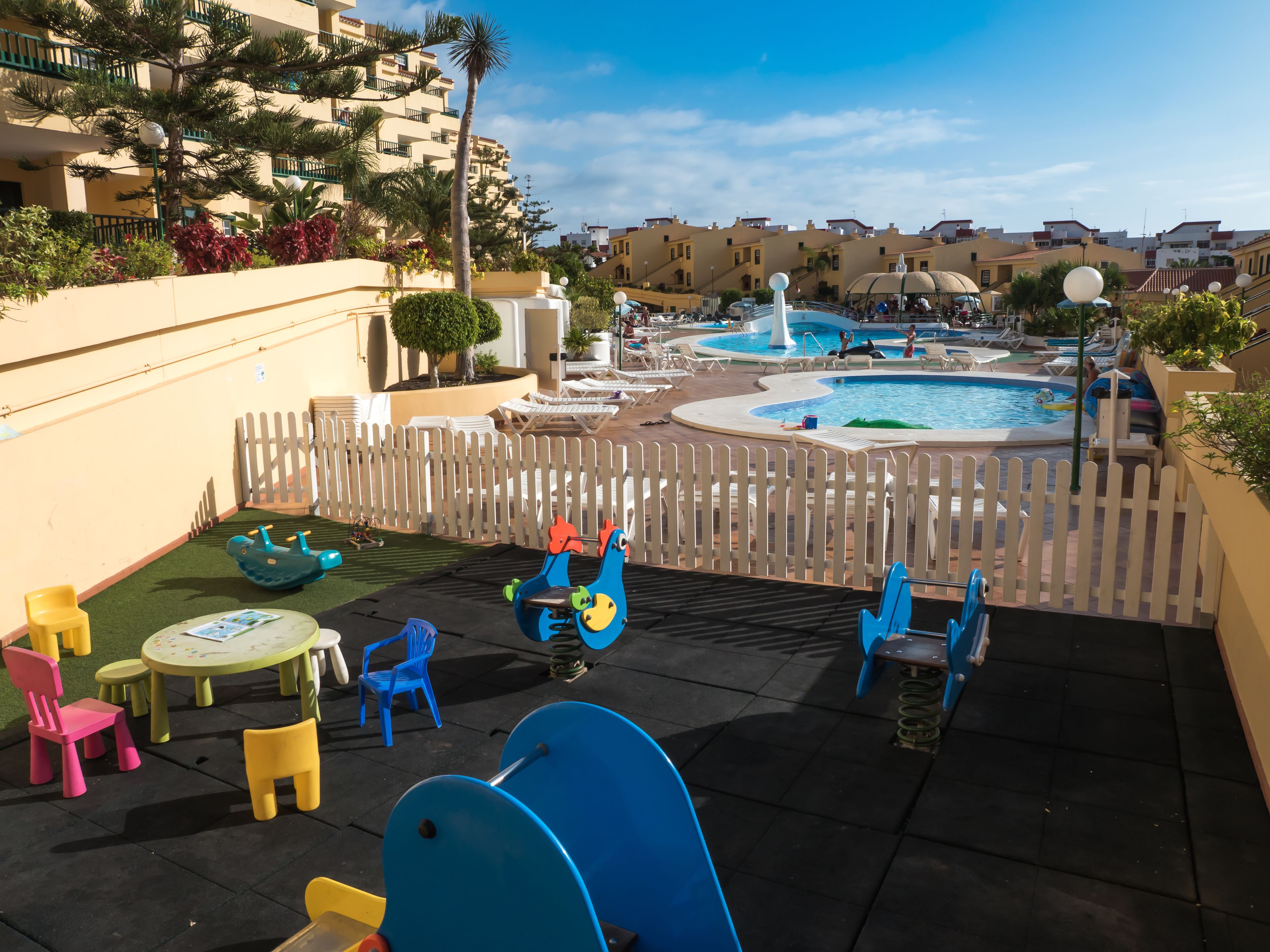 A children's play area with a slide, swings, and a small pool.