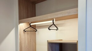 A walk-in closet with wooden shelves and drawers, and two black hangers on a light-colored shelf.