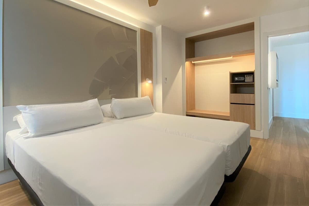 Una habitación de hotel moderna con una cama grande, armario empotrado y una pequeña kitchenette.