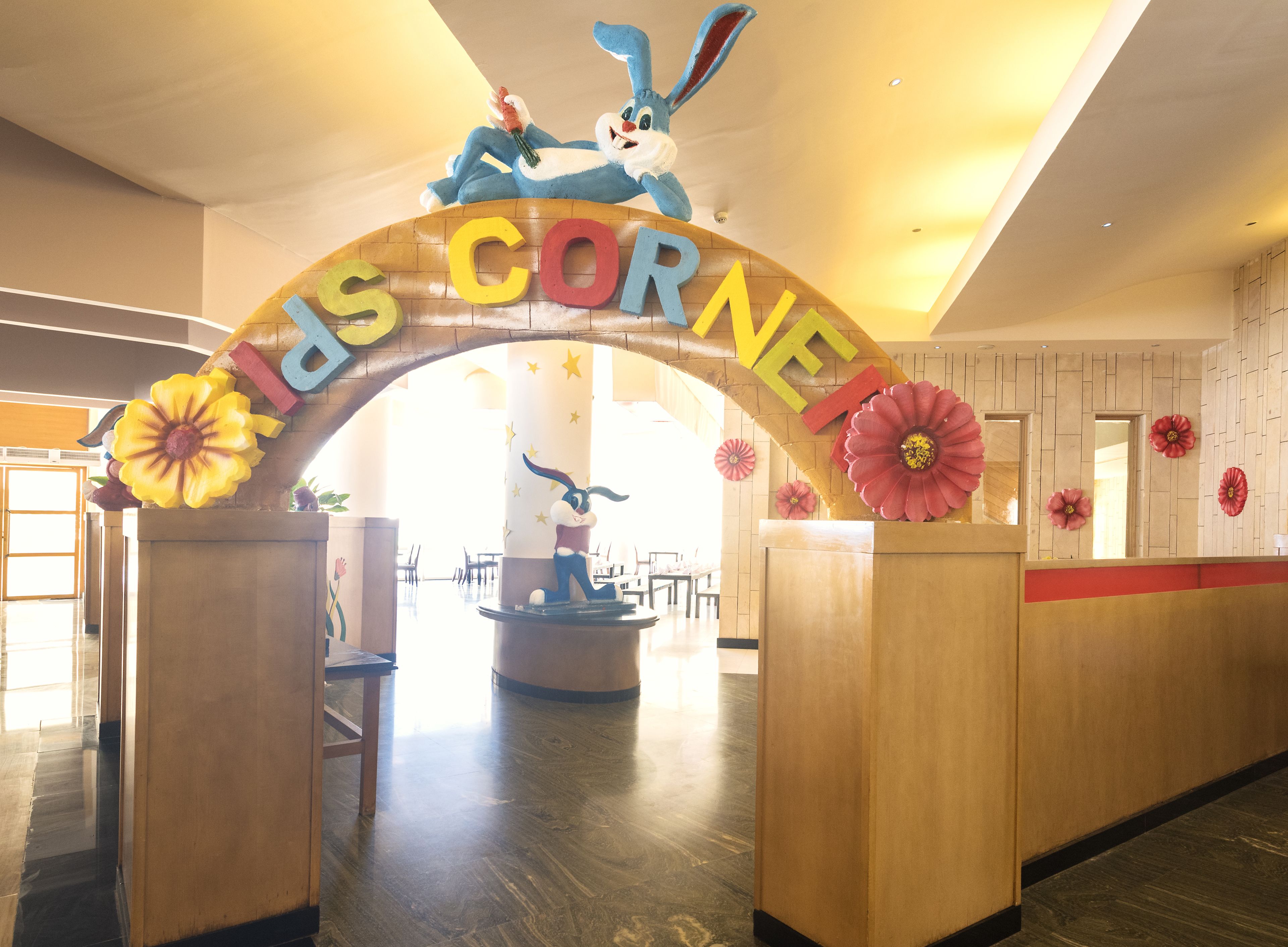 Entrada de hotel con un gran arco que presenta un conejo como mascota y las palabras 'Hotel Corner'.