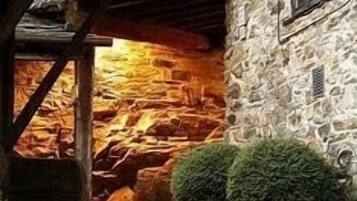 Un bâtiment en pierre doté d’une fenêtre et d’un escalier menant à une structure en bois.