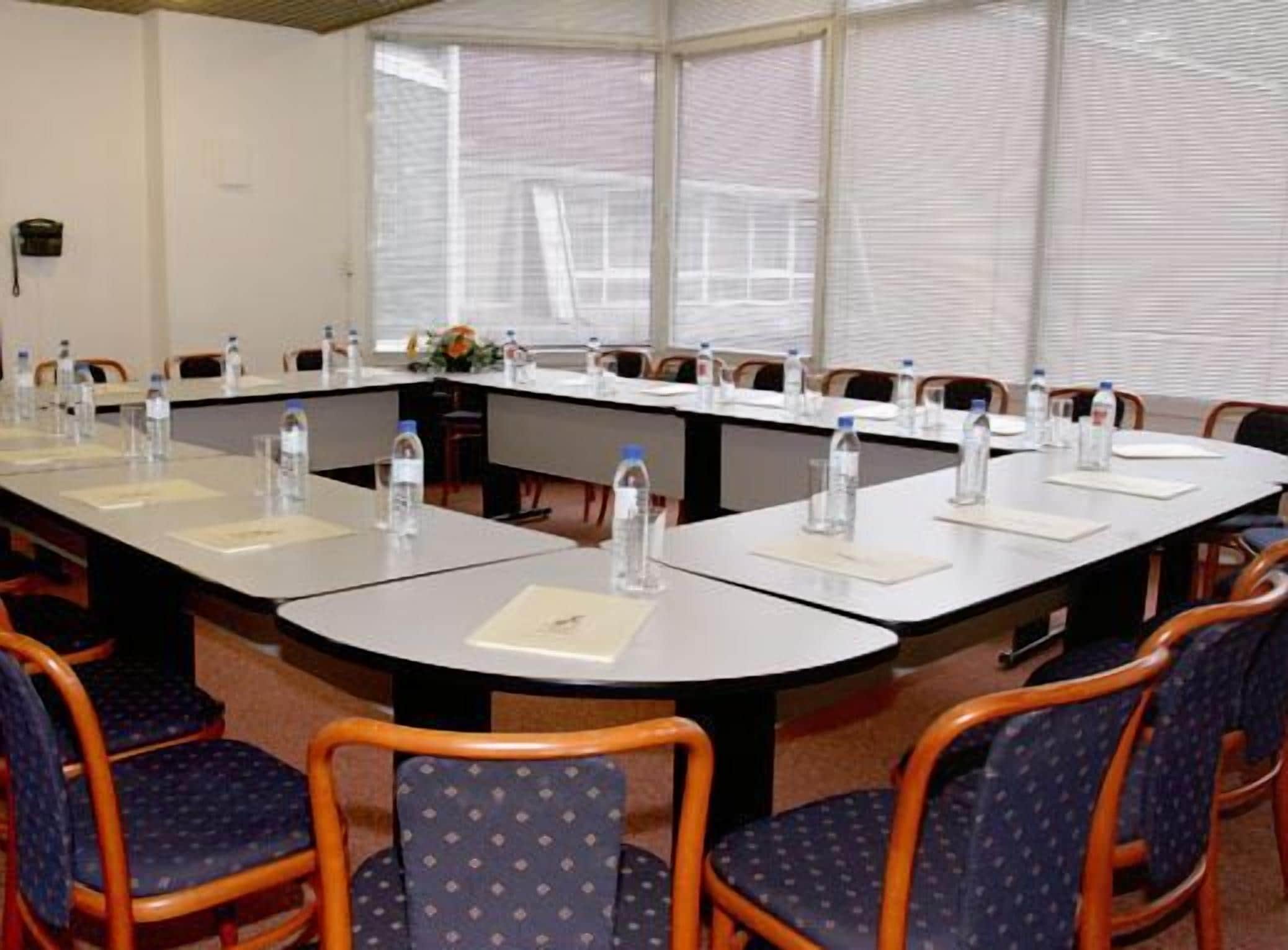A conference room with a long table, chairs, water bottles, and papers.