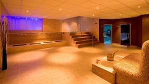A spa area with a seating area, a massage table, and a staircase leading to a shower room. - Hotel Samokov (Samokov)