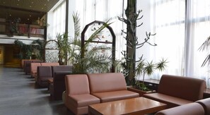 A lobby with seating areas, a staircase, and large windows.