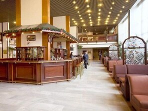 A spacious lobby with a reception desk, seating area, and a high ceiling with lights.