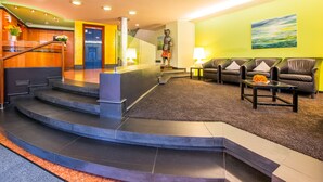 A hotel lobby with a staircase, seating area, and a reception desk. - Hotel Zum Ritter (Fulda)