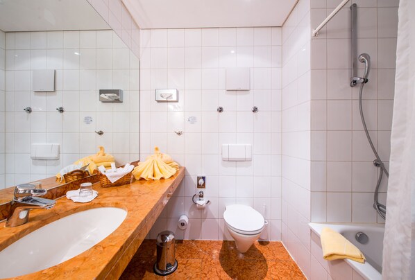 Un baño con lavamanos de mármol, inodoro, ducha y espejo.