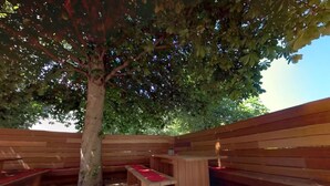 An outdoor seating area with wooden benches and a table, surrounded by a wooden fence and a tree. - Hotel Zum Ritter (Fulda)