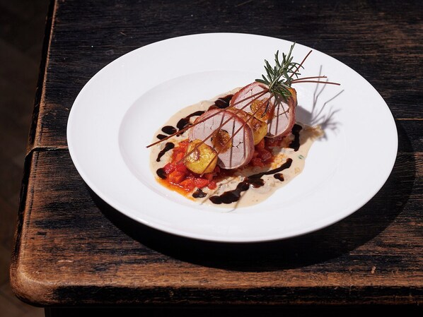 Un plato blanco con guiso de carne, verduras y salsa sobre una mesa de madera.