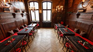 A restaurant with wooden paneling, red cushioned seating, and multiple tables. - Hotel Zum Ritter (Fulda)