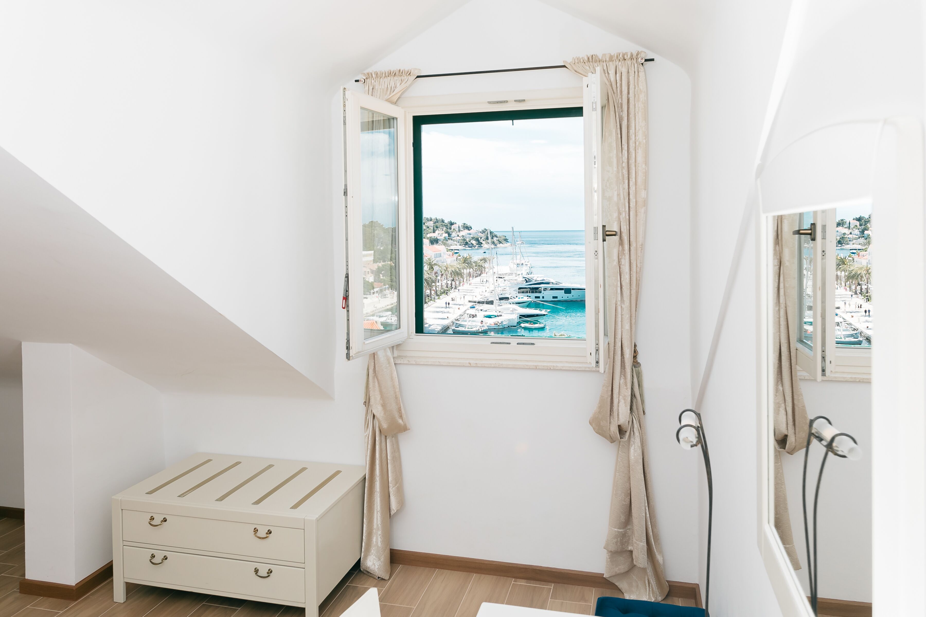 Una camera da letto con vista su un porto turistico e sul mare, un comodino e un letto con testiera.