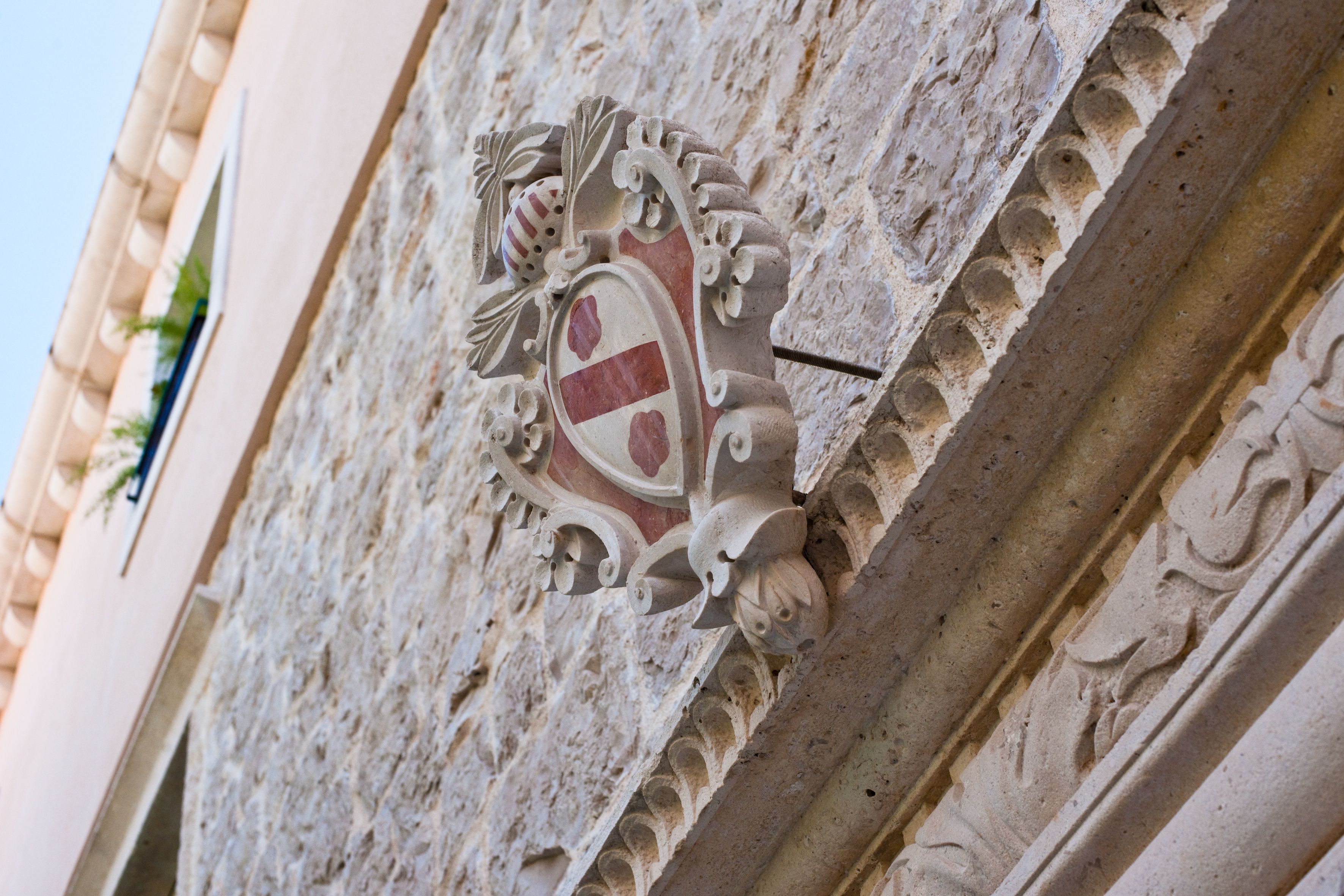 Una pared de piedra con un escudo de armas y tallas ornamentales.