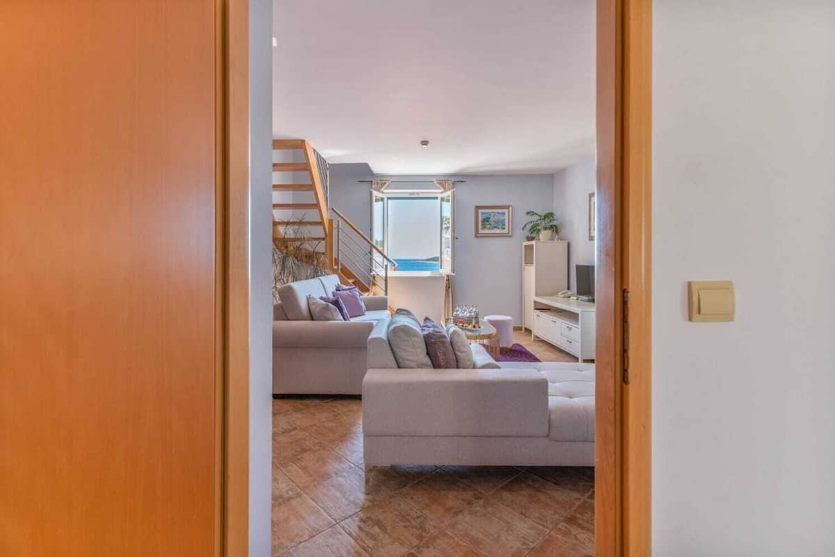 A modern living room with two sofas, a TV, and a staircase leading to an upper floor.