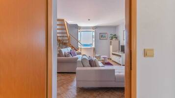 A modern living room with two sofas, a TV, and a staircase leading to an upper floor.