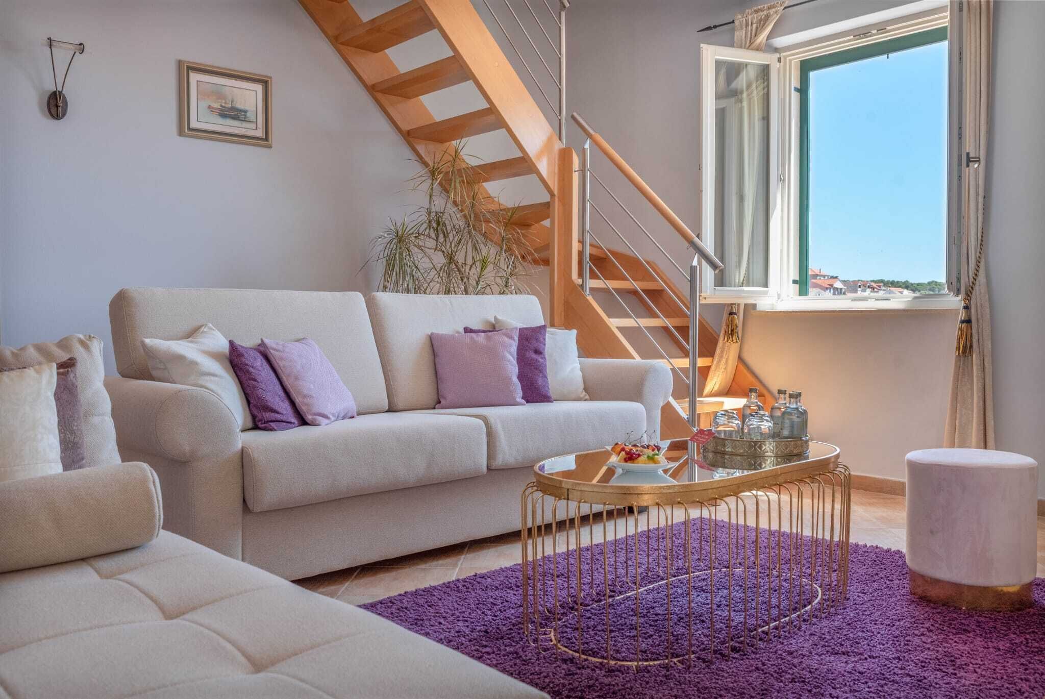 A living room with a sofa, a coffee table, a staircase, and a window with a view.