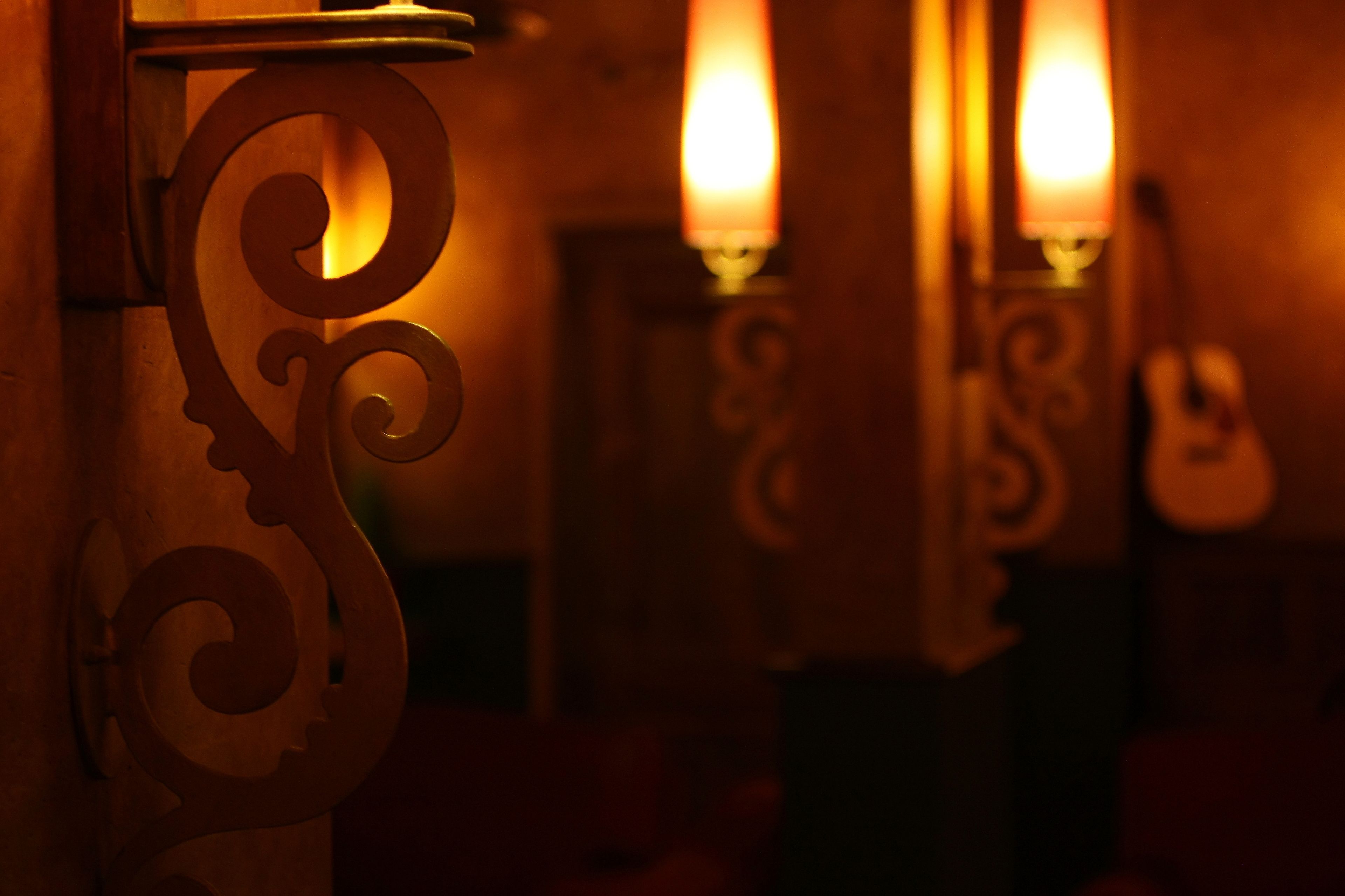 Un gros plan de chandeliers en métal décorés, diffusant une lumière chaleureuse.