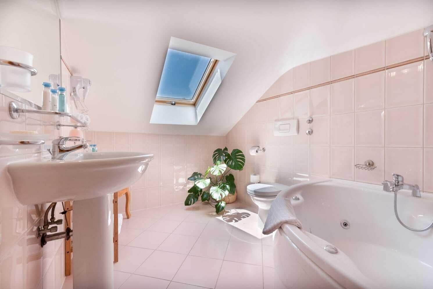A modern bathroom with a skylight, a bathtub, and a sink.