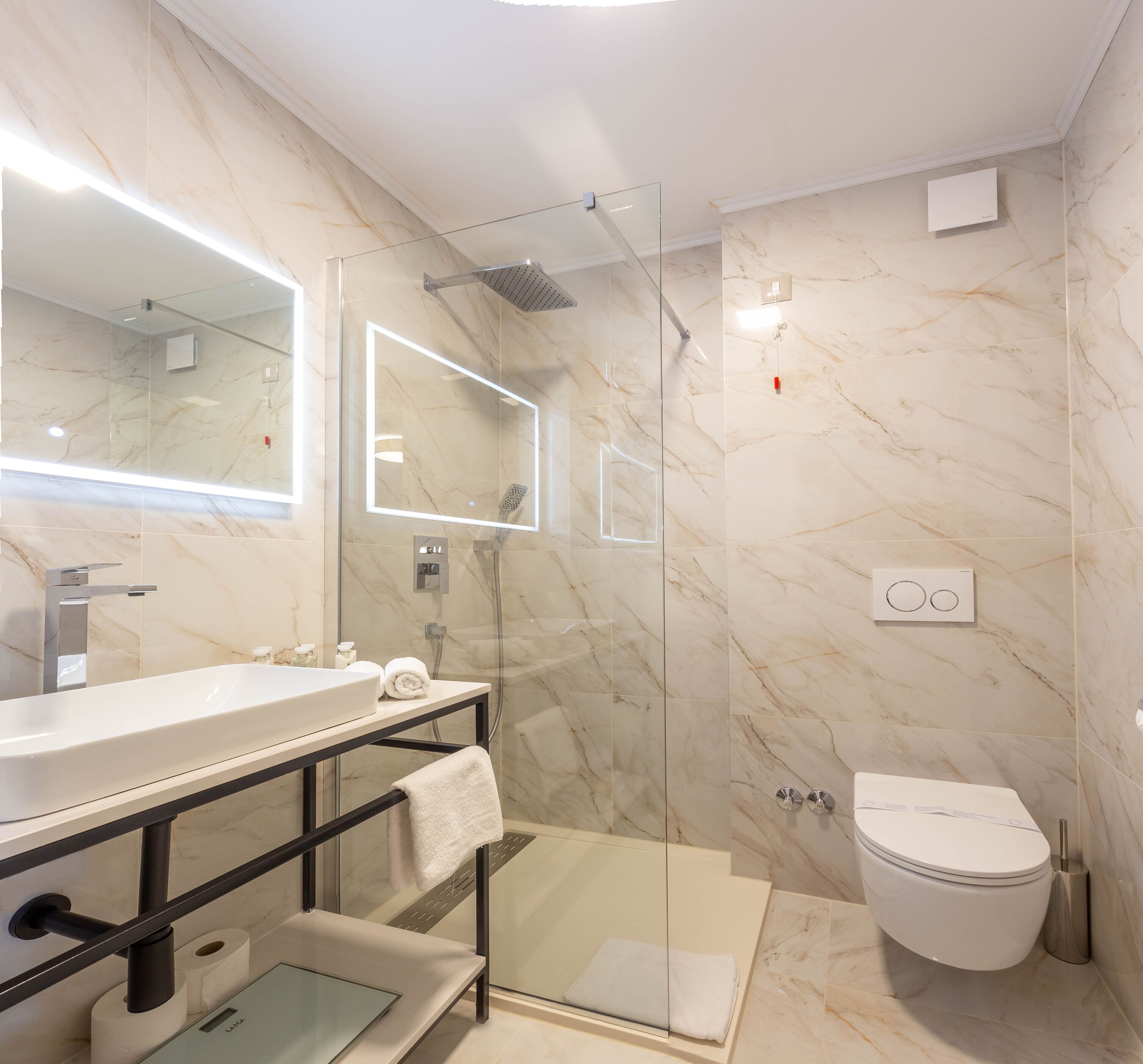Un baño moderno con ducha acristalada, lavabo blanco y retrete.