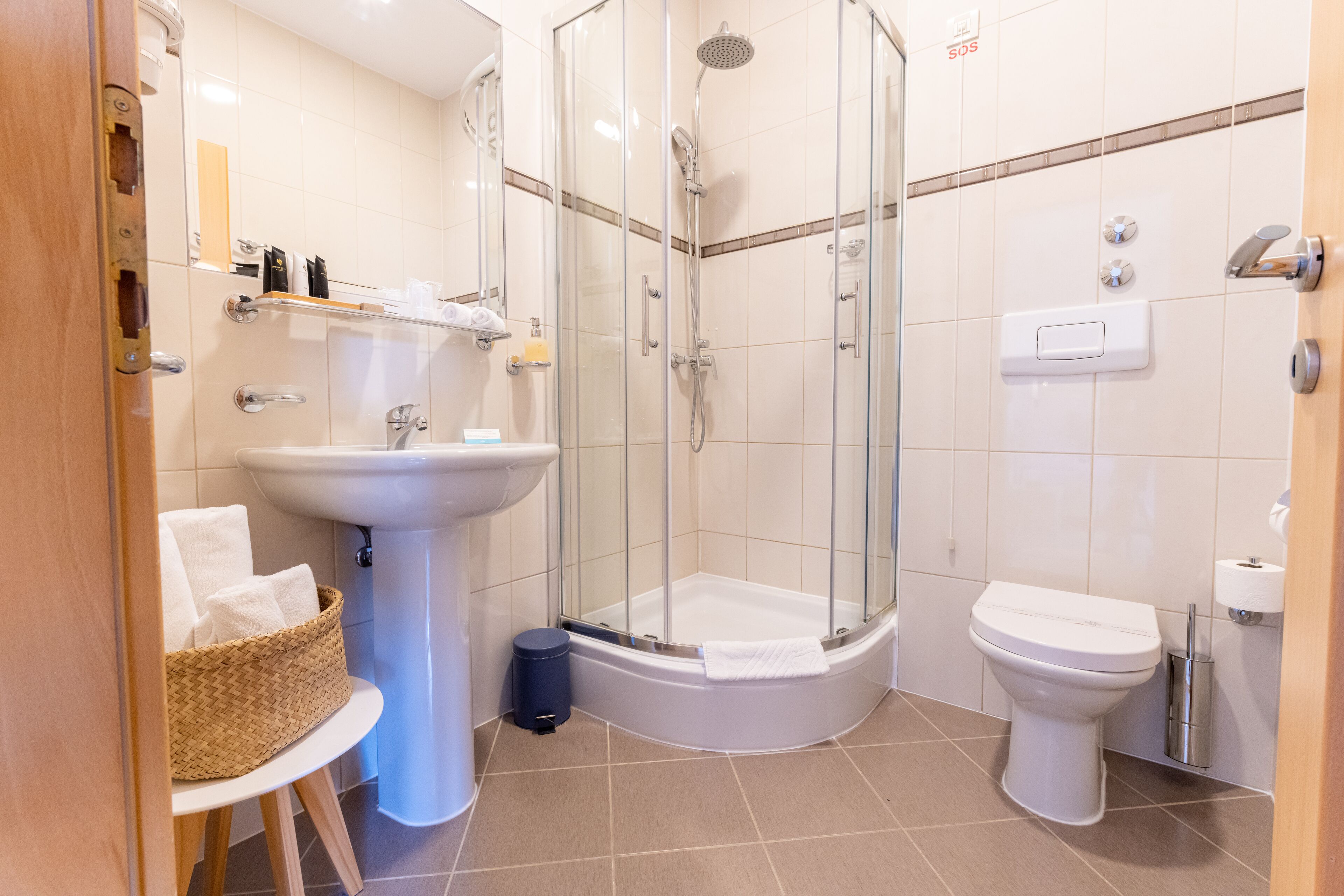 A modern bathroom with a glass-enclosed shower, a pedestal sink, and a toilet.