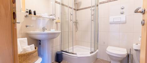 A modern bathroom with a glass-enclosed shower, a pedestal sink, and a toilet.