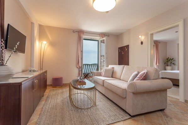 Una sala de estar moderna con un sofá, una mesa de centro, un televisor y un balcón con cortinas.