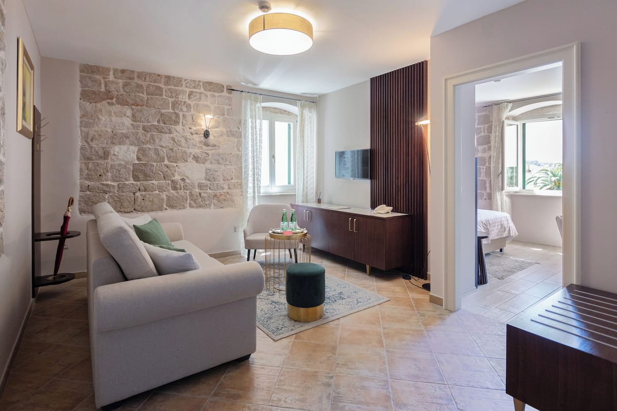 A living room with a stone wall, a sofa, a coffee table, and a TV.