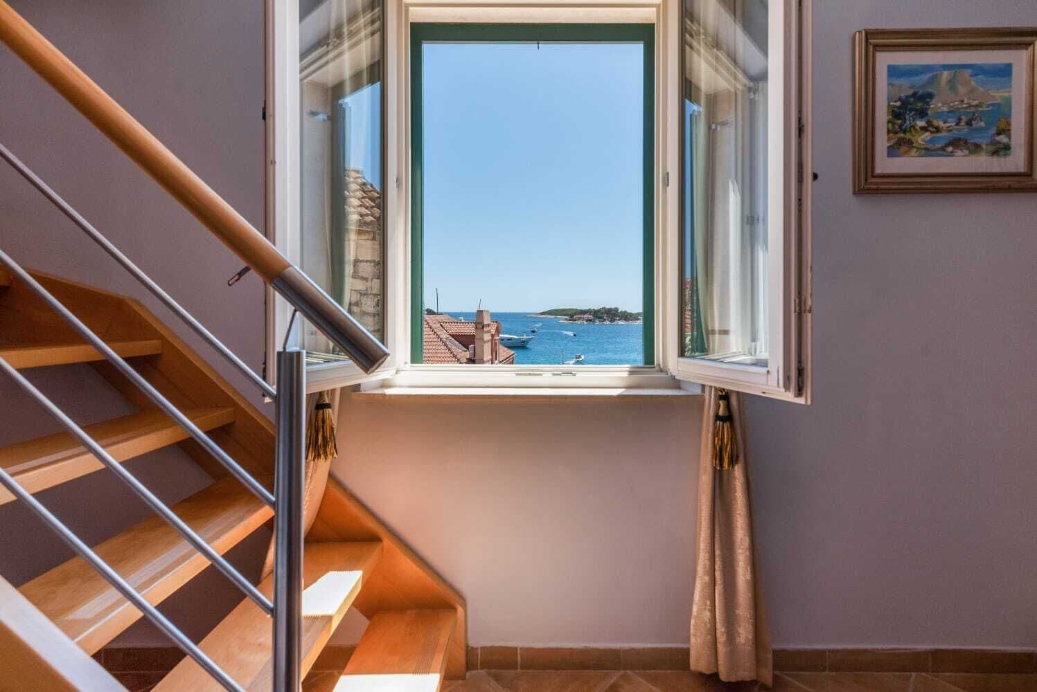 A staircase leading to a balcony with a clear view of the sea and boats.