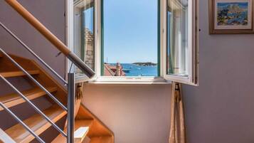 A staircase leading to a balcony with a clear view of the sea and boats.