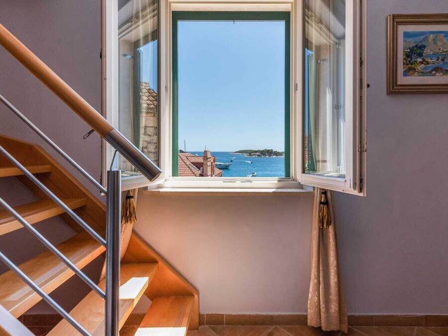 Escadas levam a uma varanda com vista desobstruída para o mar e barcos.