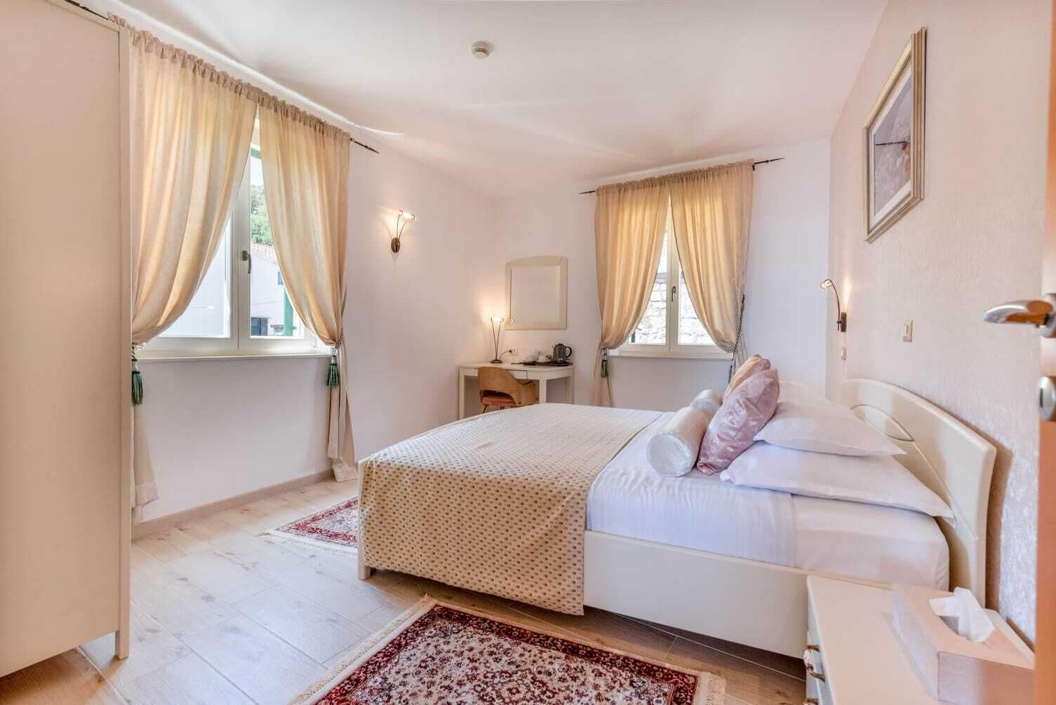 A bedroom with a bed, a desk, a chair, and a window with curtains.