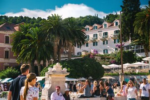 Un hotel con fachada blanca, balcones y una fuente en la parte delantera.