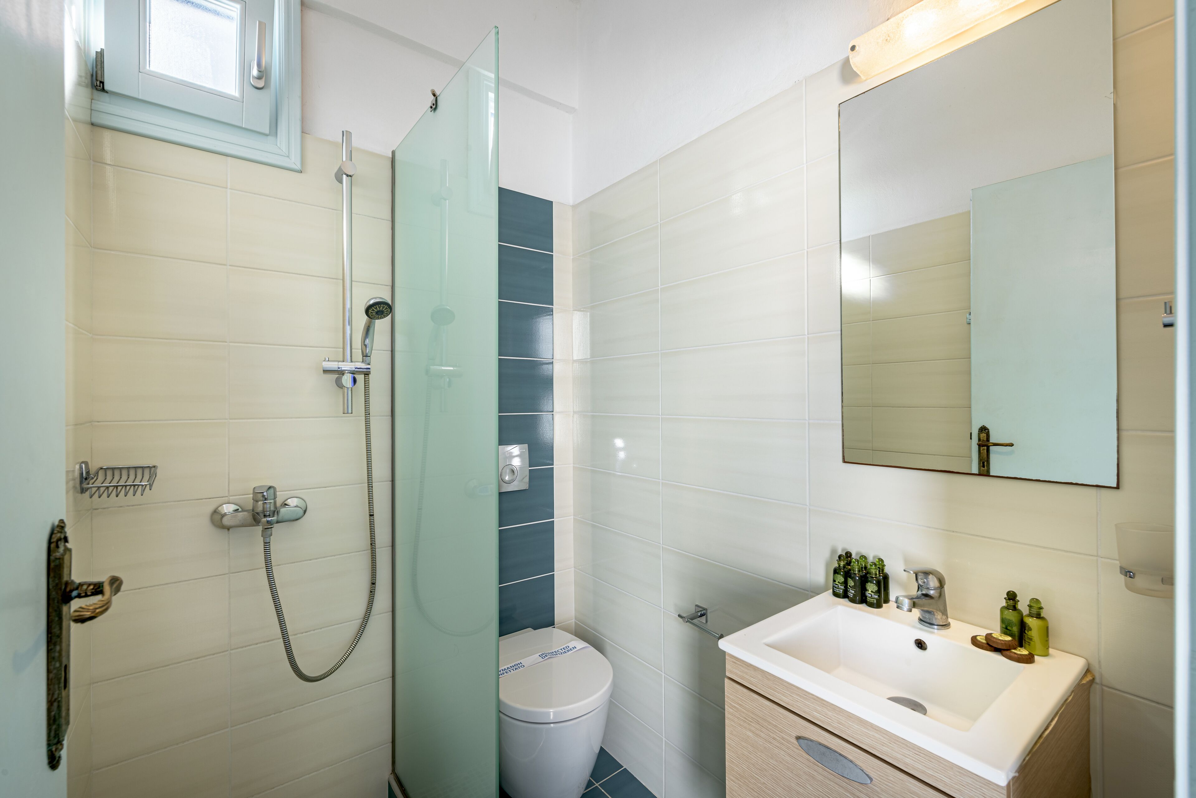 A bathroom with a shower, toilet, sink, and mirror.