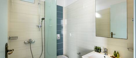A bathroom with a shower, toilet, sink, and mirror.