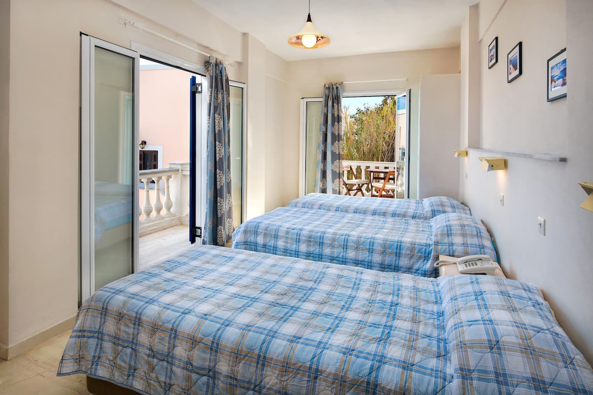 A bedroom with two beds, a balcony, and a view of the outdoors.