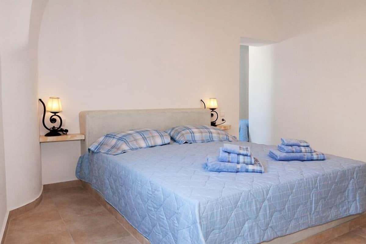 A bedroom with a bed, two bedside lamps, and a nightstand.