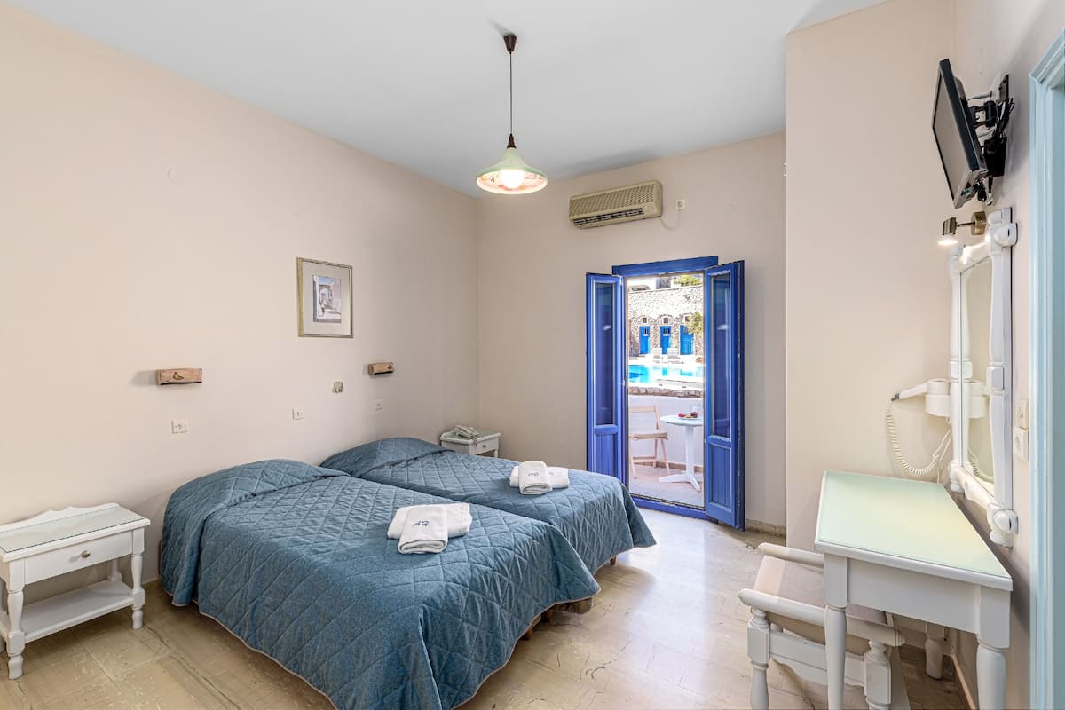 A room with two beds, a desk, a chair, a telephone, and a door leading outside.