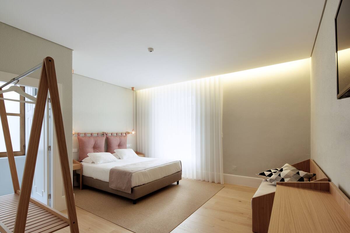A modern bedroom with a bed, a wooden desk, and a hanging chair.