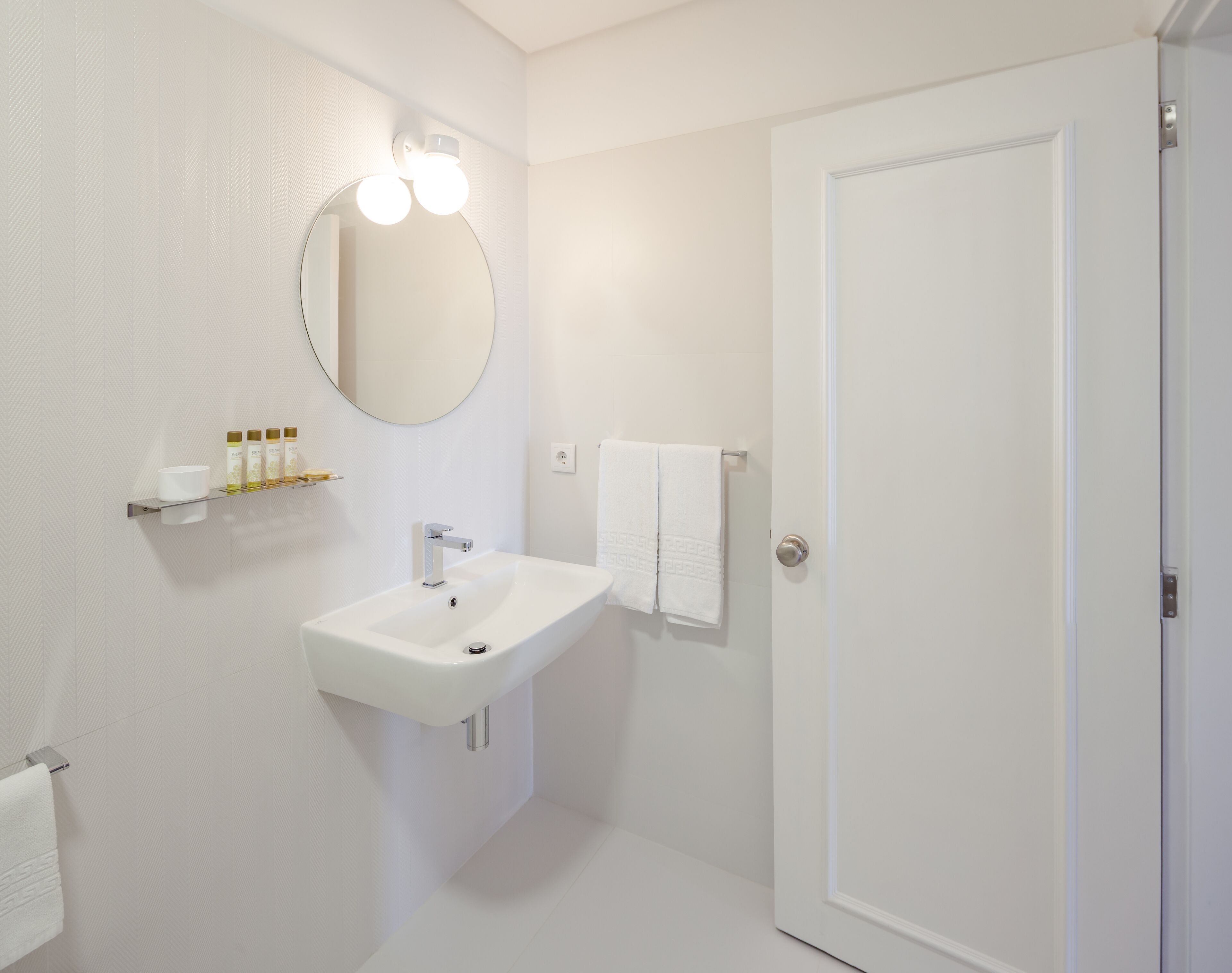 A bathroom with a white sink, a mirror, and a towel rack.