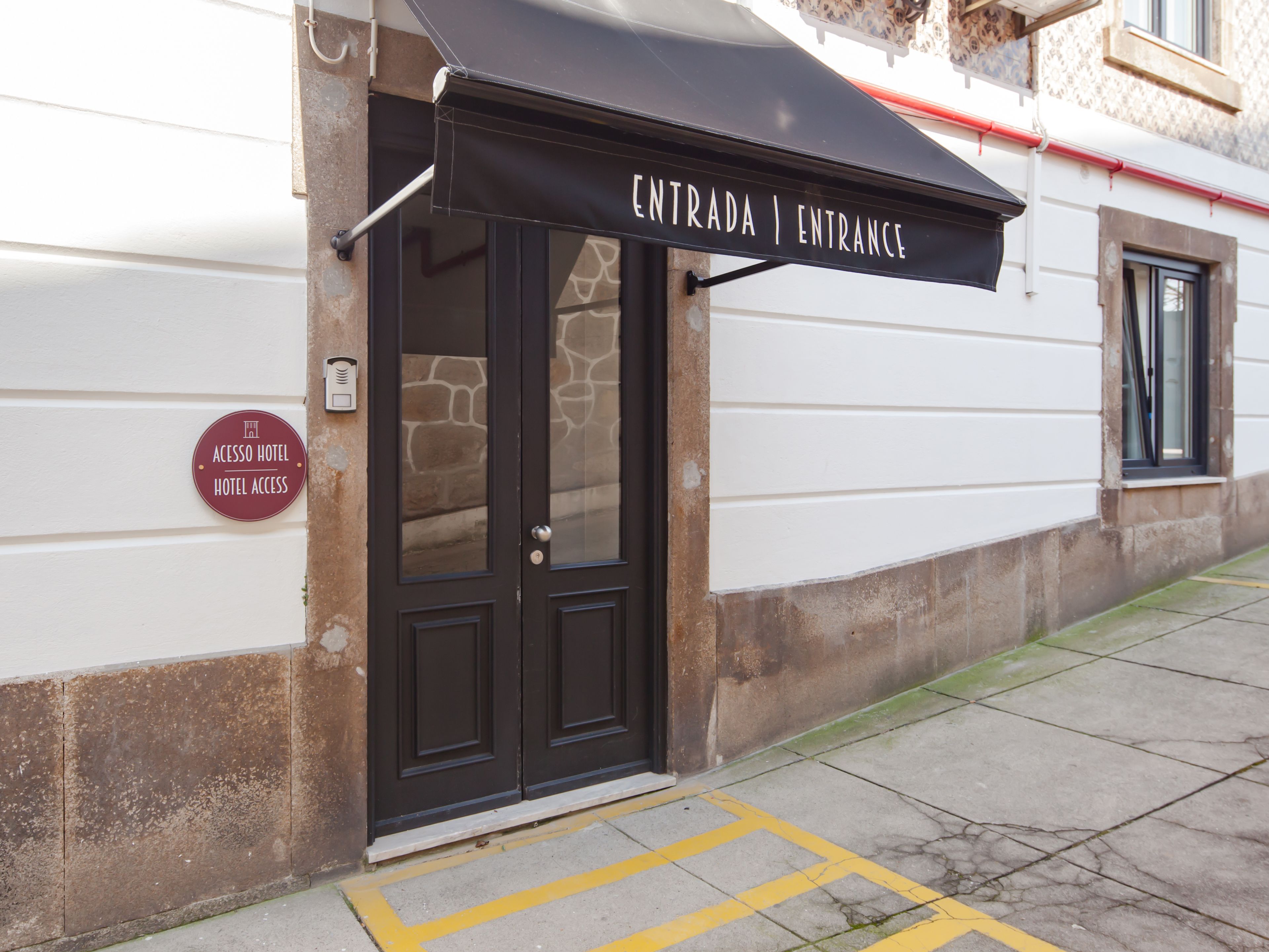 A hotel entrance with a black awning displaying "ENTRADA | ENTRANCE".