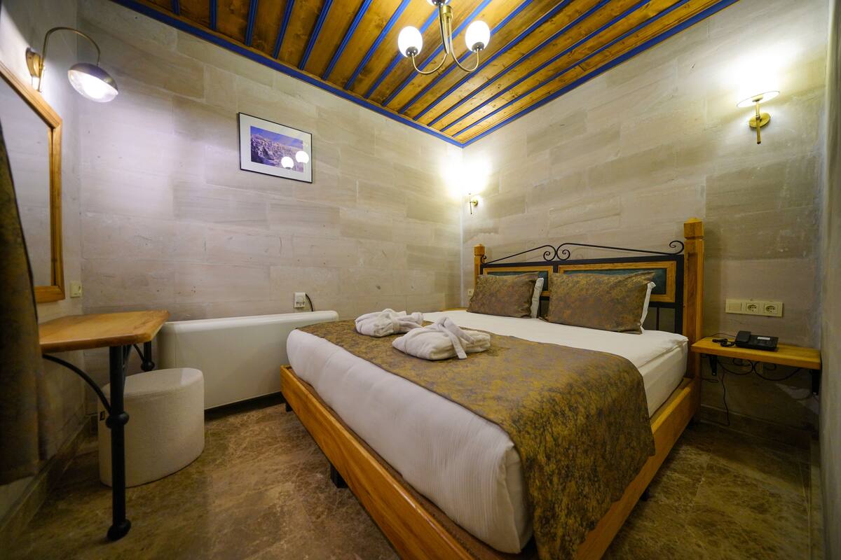 Ein Schlafzimmer mit einem hölzernen Bett, einem Nachttisch aus Holz, einer Wandlampe und einem Bild an der Wand.