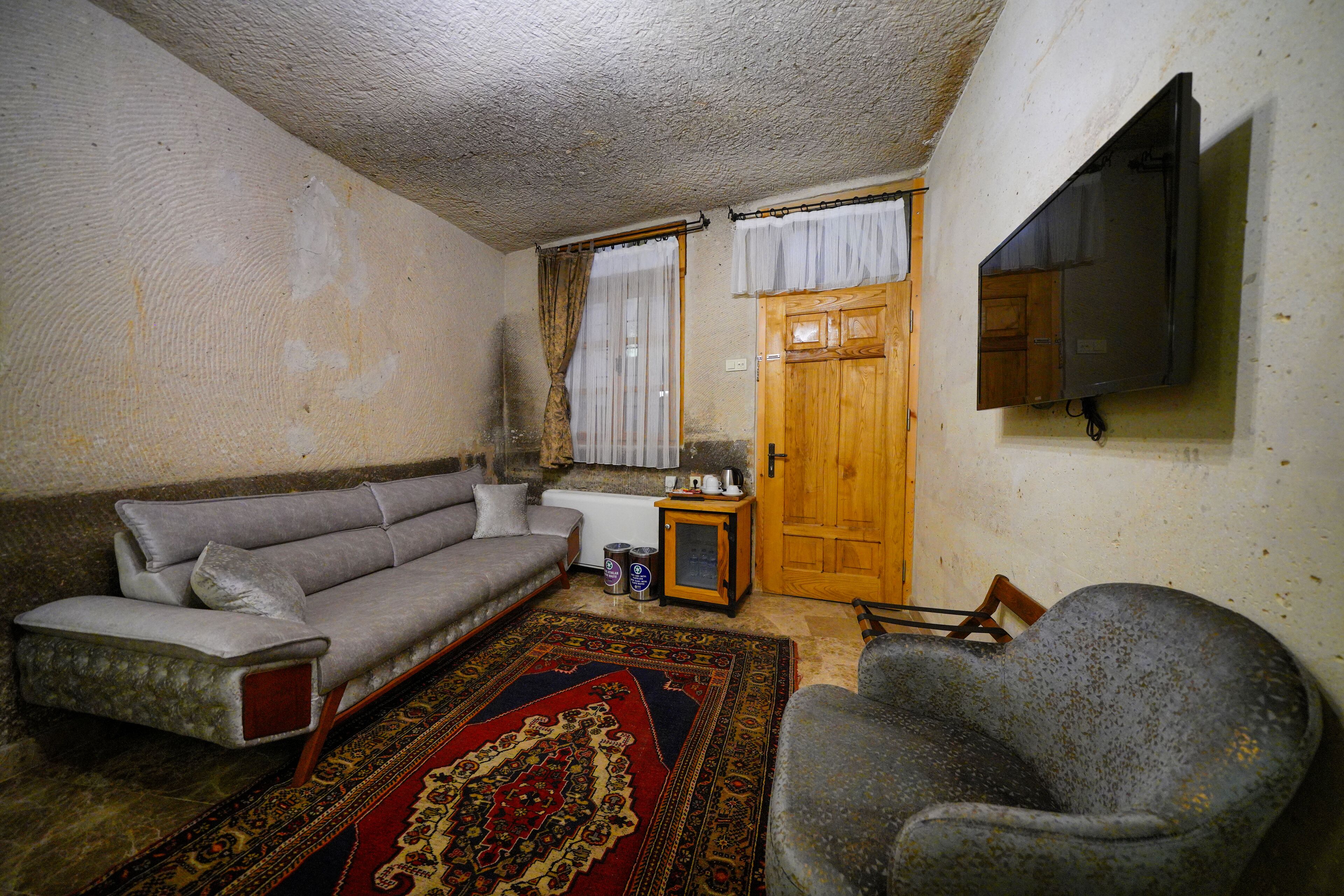 A living room with a sofa, armchair, and a television mounted on the wall.