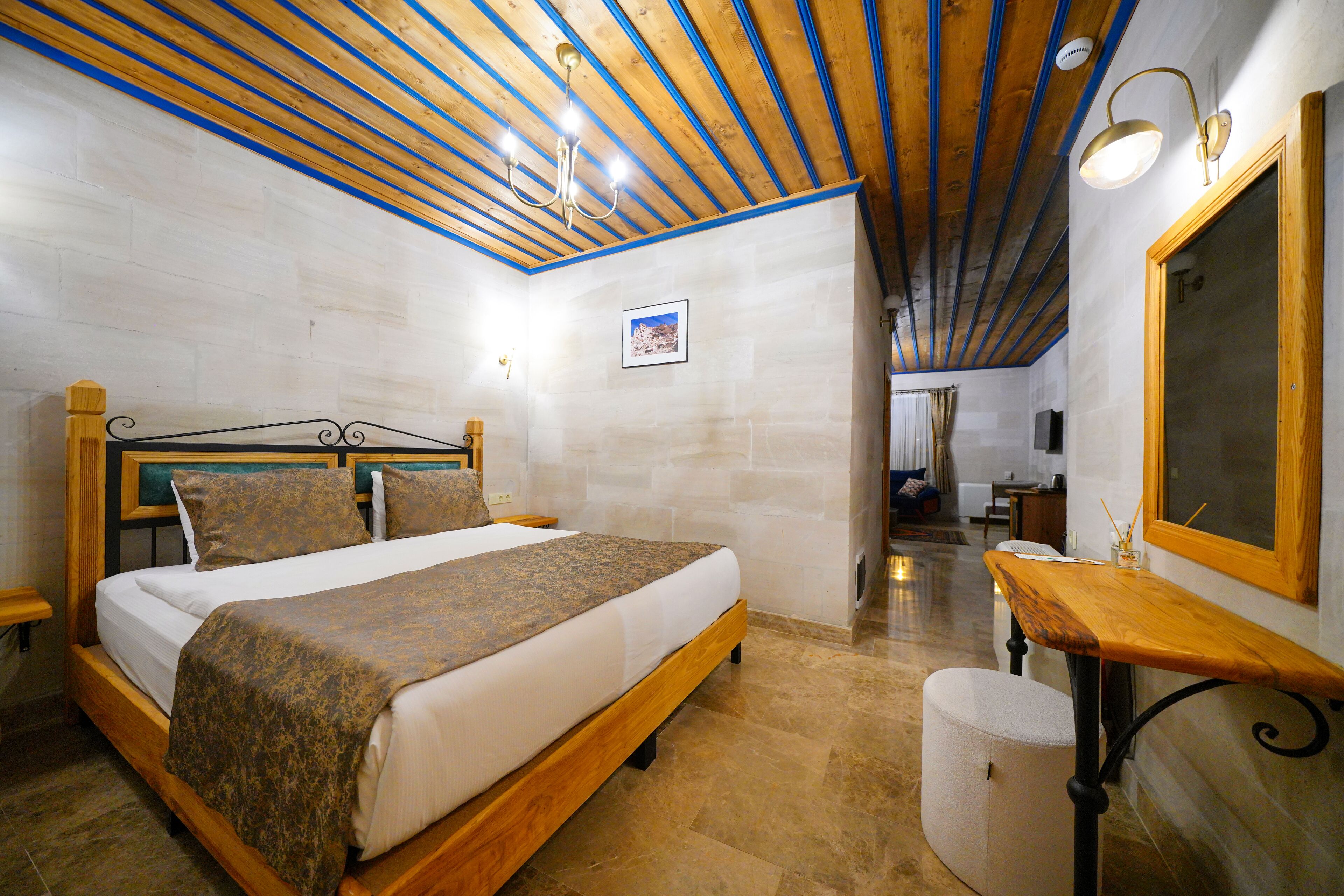 Een slaapkamer met een houten bed, nachtkastje en spiegel.