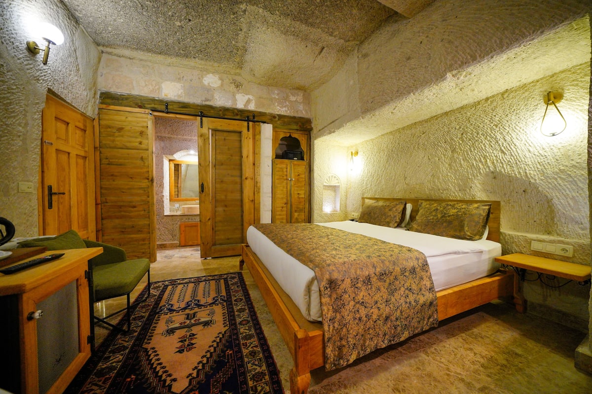 Ein rustikales Schlafzimmer mit einem hölzernen Bett, einem grünen Stuhl, einem kleinen Schreibtisch und einem Spiegel.