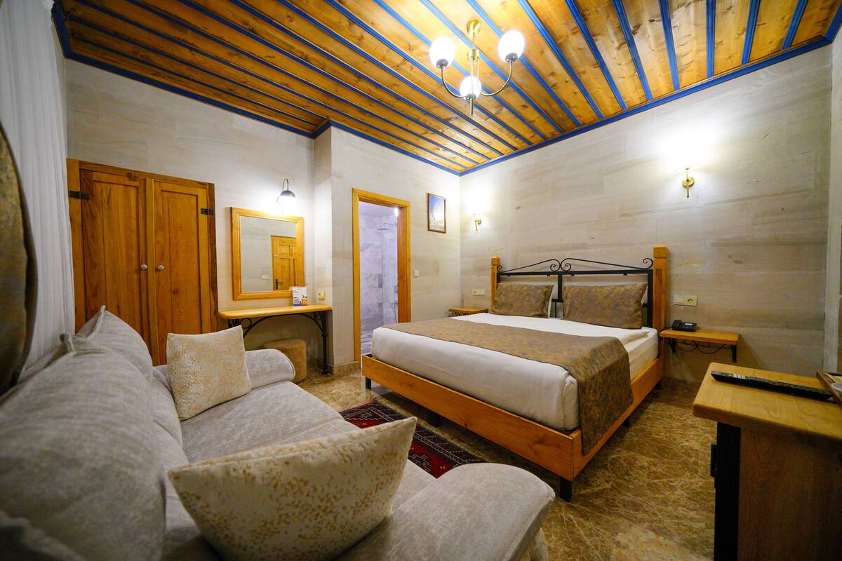 Ein Schlafzimmer mit Holzboden, einem Bett, einem hölzernen Schreibtisch und einem Spiegel.