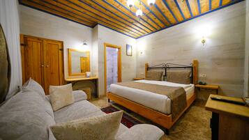 A bedroom with a wooden ceiling, a bed, a wooden desk, and a mirror.