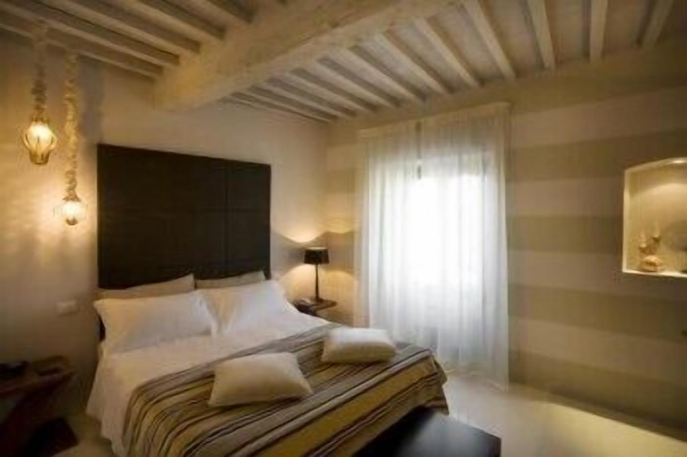 A bedroom with a bed, bedside tables, a lamp, and a window with curtains.