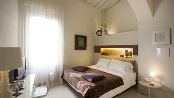 Ein Hotelzimmer mit Bett, Nachttisch, Lampe und Schreibtisch mit Stuhl.